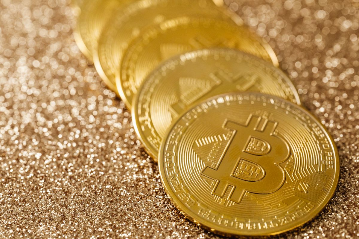 Koin Bitcoin bertumpuk di depan layar grafik perdagangan kripto