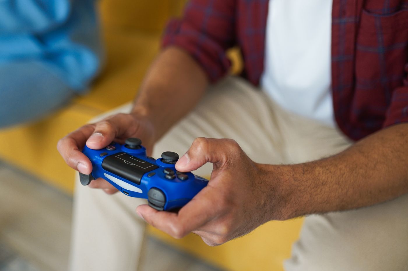 Tangan memegang controller wireless di atas sofa